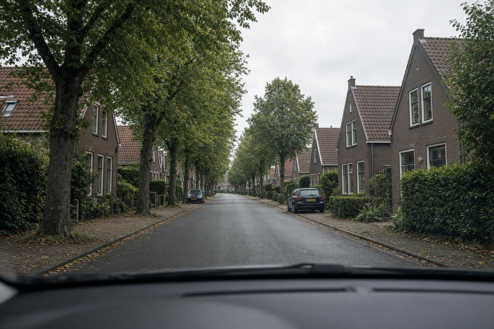 Uitzicht door de voorruit op een rustige Nederlandse straat.